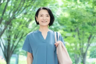 鞄を持って歩きだす50代女性の画像