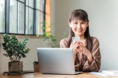 パソコンとスマートフォンで仕事探しをする50代女性の画像